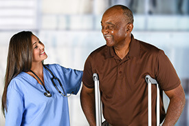Patient Care Assistant helping man on crutches