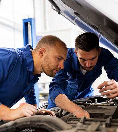 auto service technicians looking at car engine
