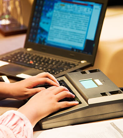  court reporters hands on a stenography machine