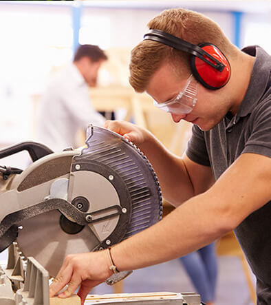 Carpentry student at saw table cuttong wood